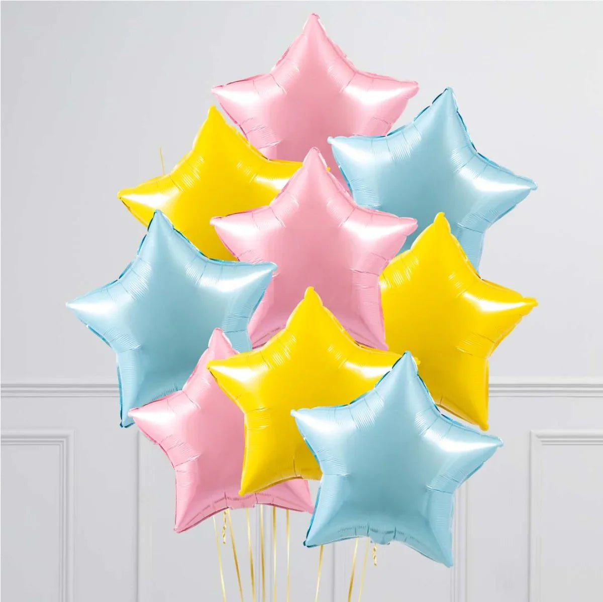 Cluster of pastel pink, yellow, and blue star-shaped foil balloons against a plain white wall