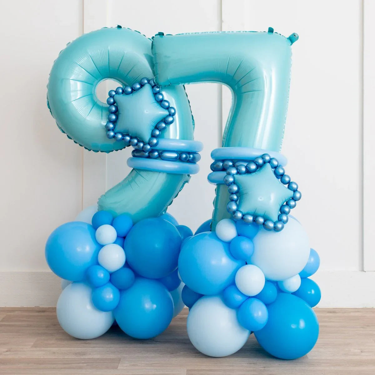 Baby blue number 97 foil balloons decorated with star balloon and bunch of blue balloons on wooden floor