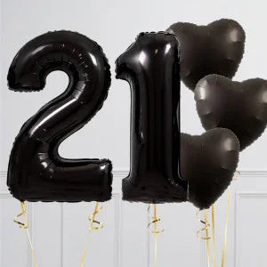Black foil balloons shaped as number 21 and heart against white background, Dubai