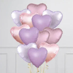 Lavender, rose pink, and silver heart-shaped balloons bouquet against a light gray wall in Dubai