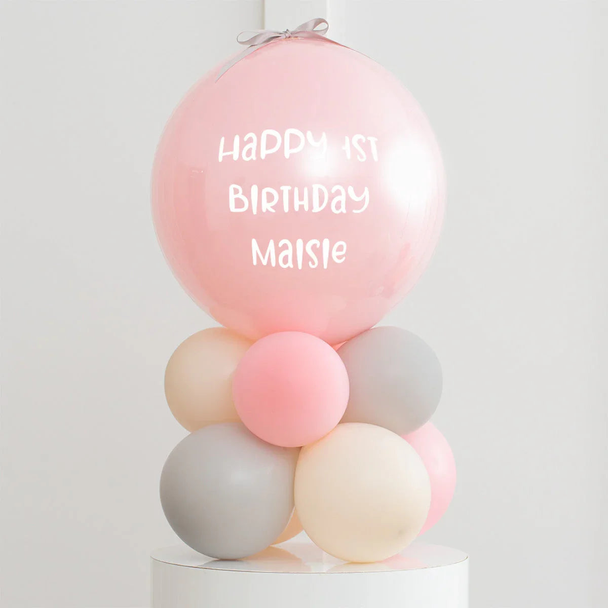 Personalised pink balloon with 'Happy 1st Birthday Maisie' on pastel balloon cluster