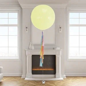 Yellow helium giant balloon with rainbow tassel tail in elegant living room in Dubai