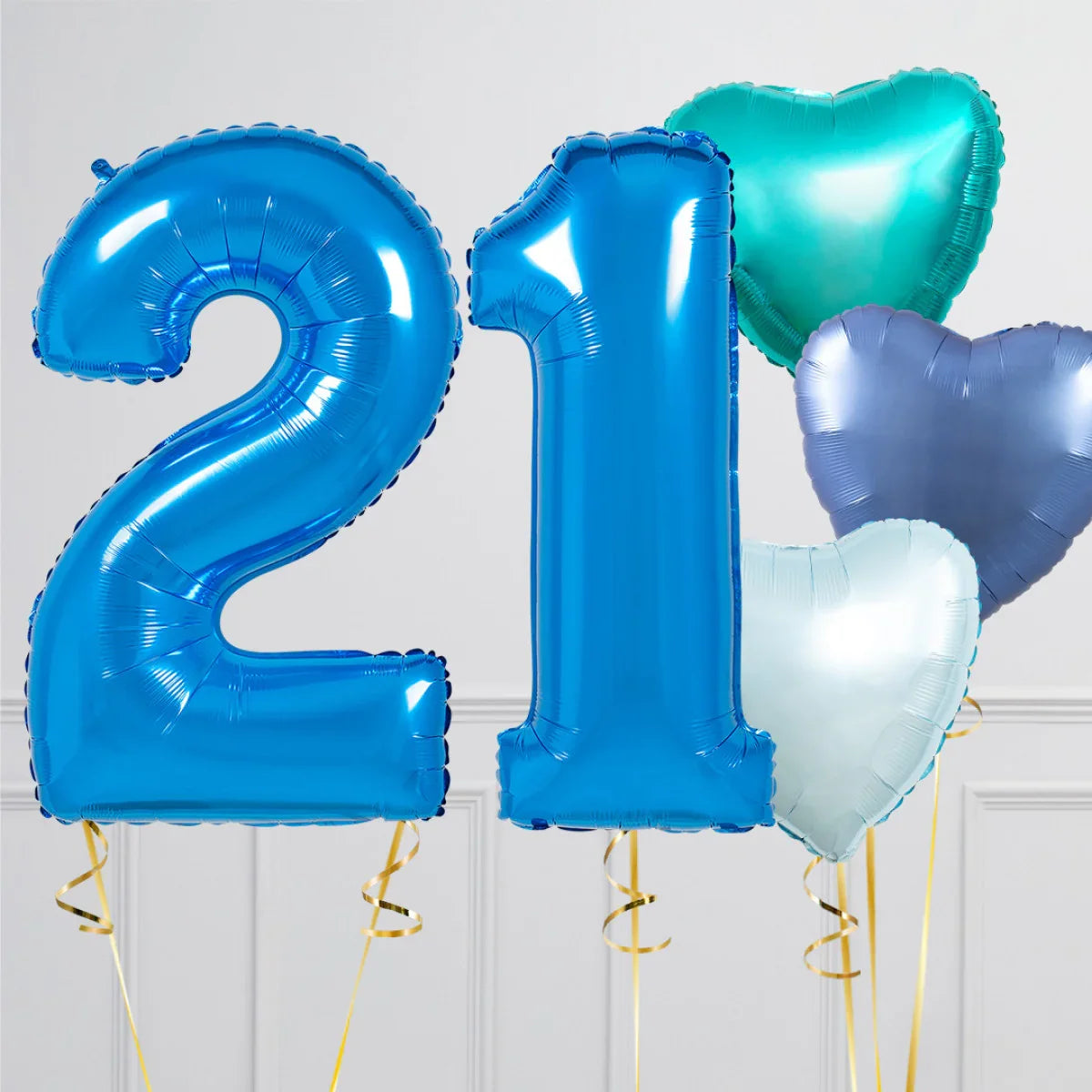 Blue foil balloons shaped as the number 21 with green and silver heart-shaped balloons on gold strings