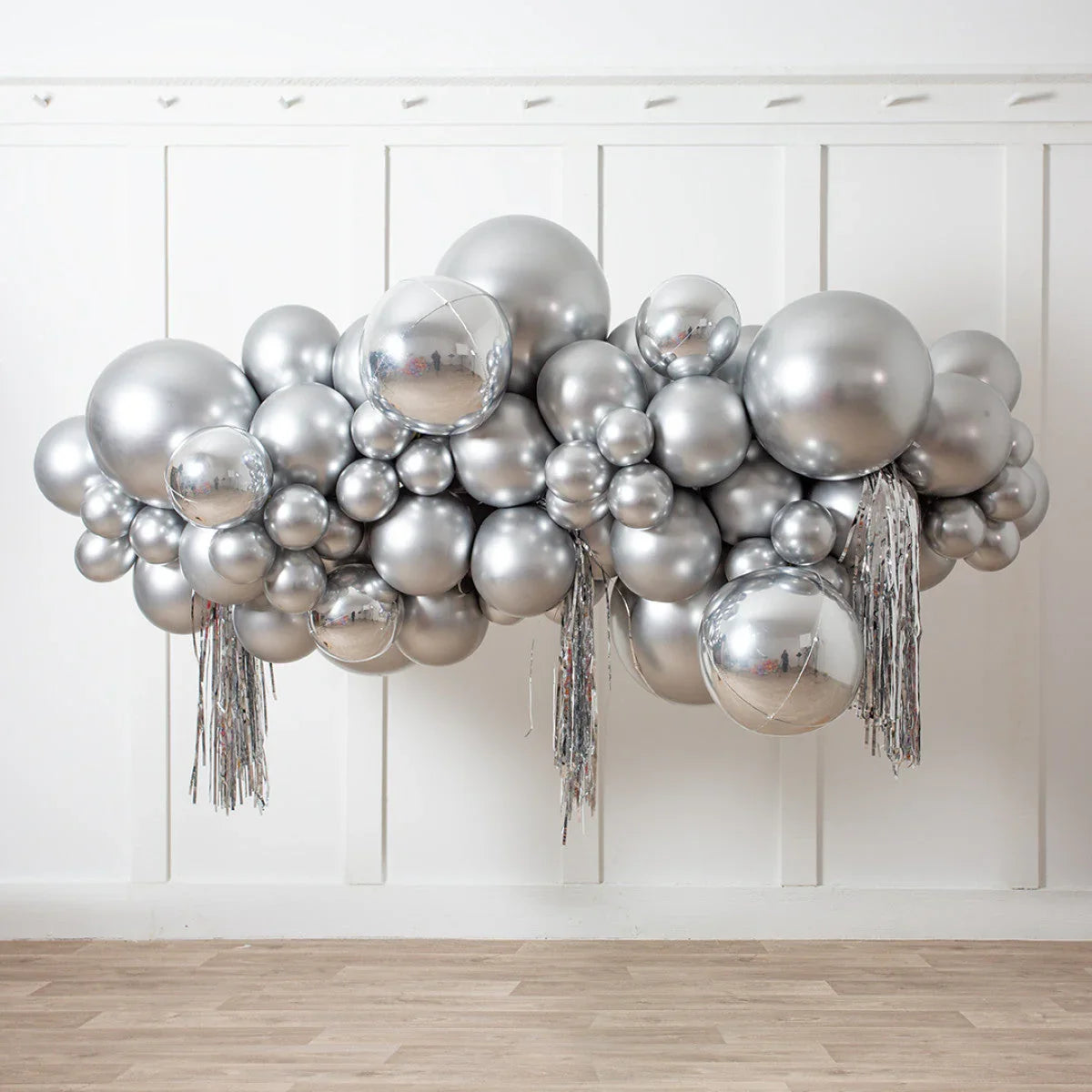 Decorative silver chrome balloon garland with tassels against white paneled wall