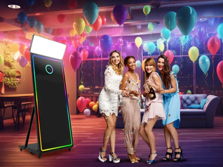Four women celebrating with drinks near colorful balloon-decorated VIP photo booth mirror in party room