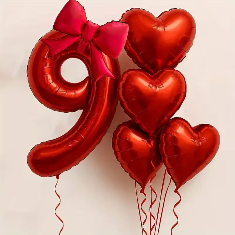 Red foil balloon shaped as number 9 with bow and four red heart-shaped foil balloons on ribbons