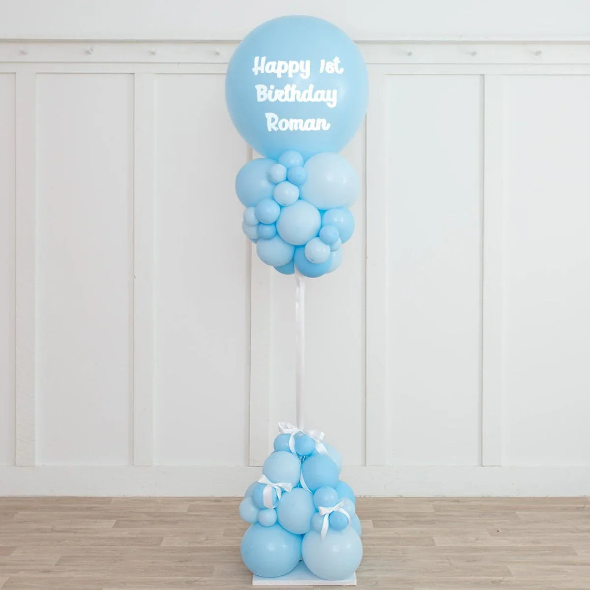 Blue balloon pillar decoration with Happy 1st Birthday Roman text for kid's party