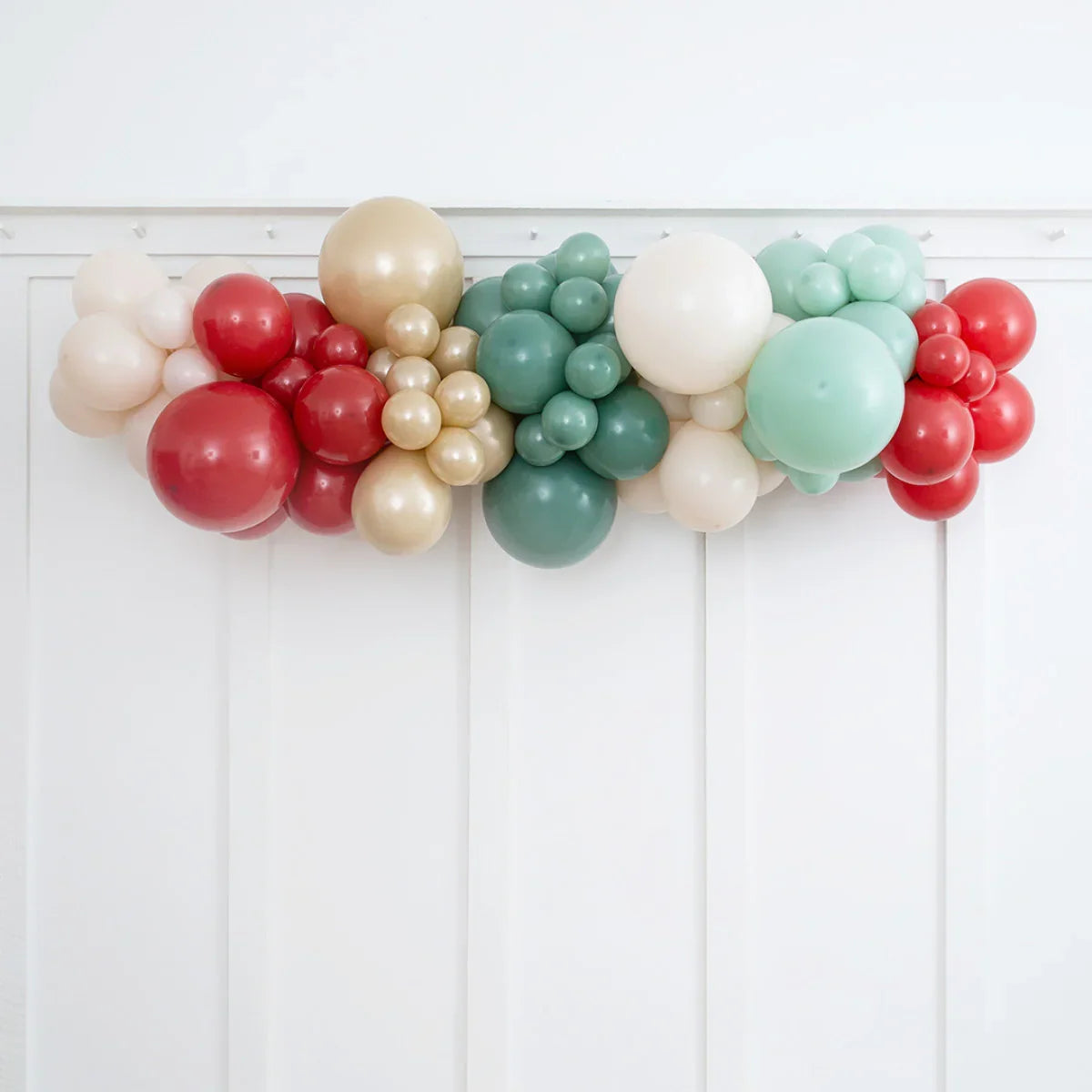 Classic Christmas balloon garland in red, gold, white, and green on white wall