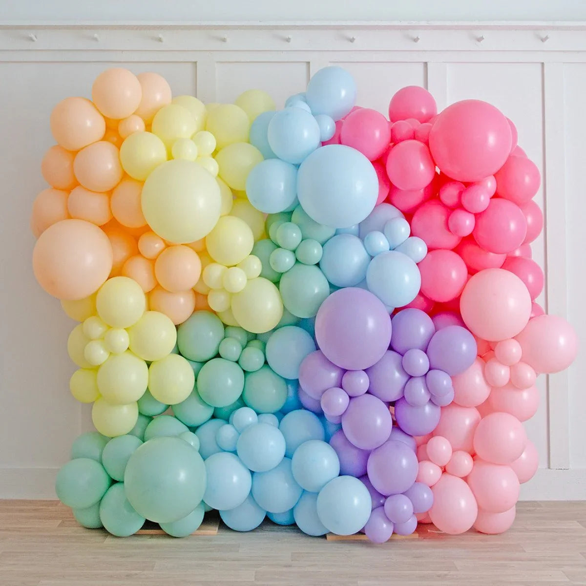 Pastel rainbow balloon wall decoration in a modern indoor party setting
