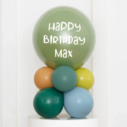 Personalised green birthday balloon with text Happy Birthday Max stacked with colorful air-filled balloons