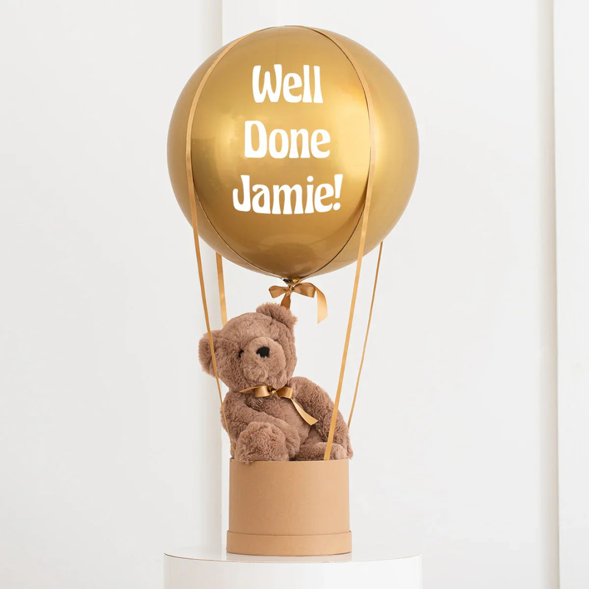 Gold balloon with 'Well Done Jamie!' text and teddy bear in gift box, decorative celebration gift
