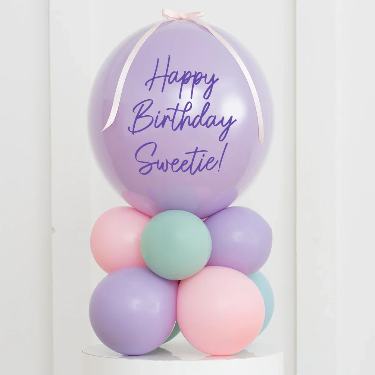 Personalised pastel balloon stack with 'Happy Birthday Sweetie!' message on lavender air-filled bubble balloon