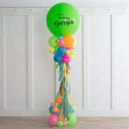 Colorful birthday balloon pillar with green top balloon reading Happy Birthday Georgia, decorated with vibrant balloons and tassels