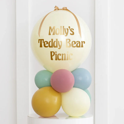 Personalised pastel balloon stack with "Molly's Teddy Bear Picnic" text, mint, pink, mustard colors