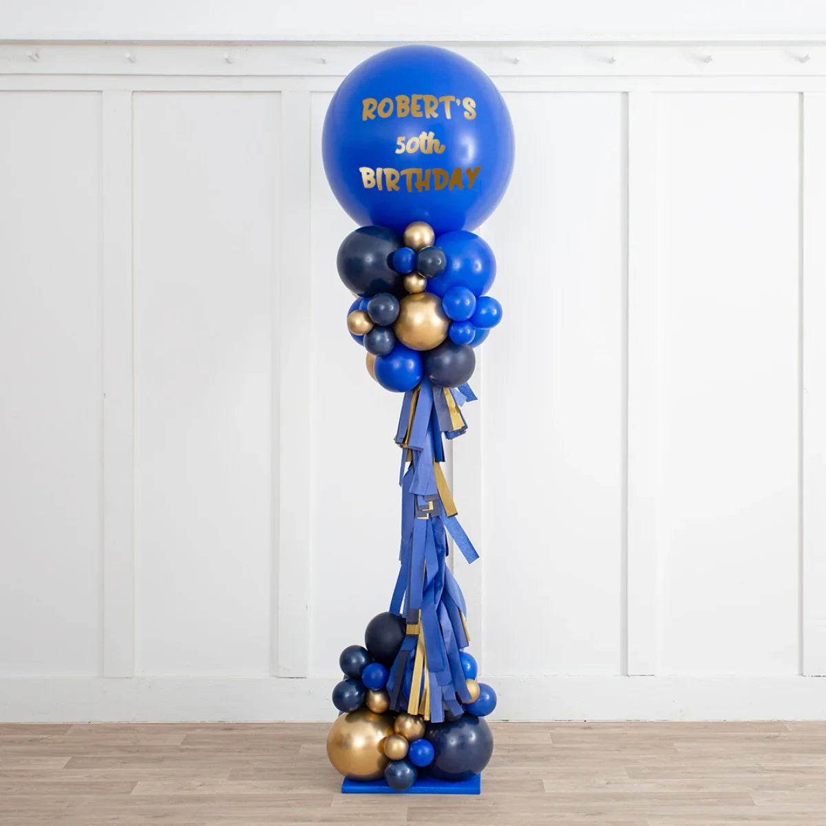 Personalised sapphire blue and gold balloon pillar with tassels for Robert's 50th birthday celebration