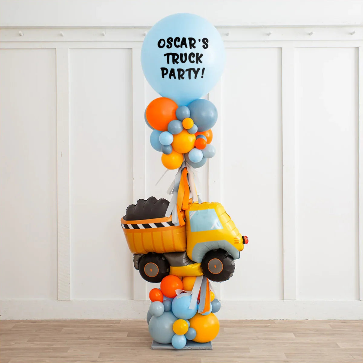 Personalized balloon pillar with yellow dump truck and blue balloon reading 'Oscar's Truck Party'
