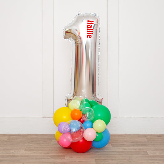 Personalized 26" Silver Foil Number Balloon on Colorful Rainbow Stack