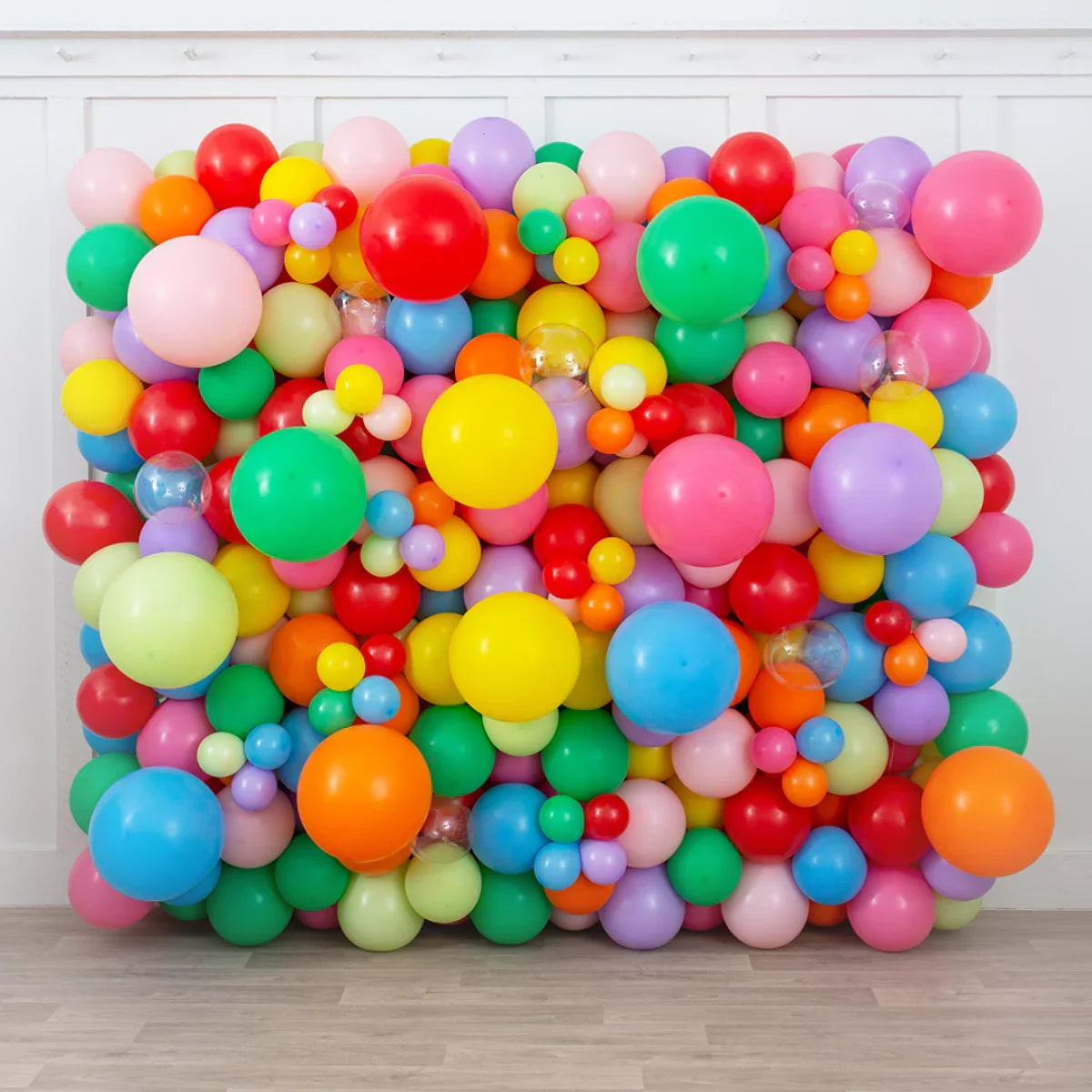 Colorful rainbow balloon wall with assorted sizes for party backdrop on wooden floor