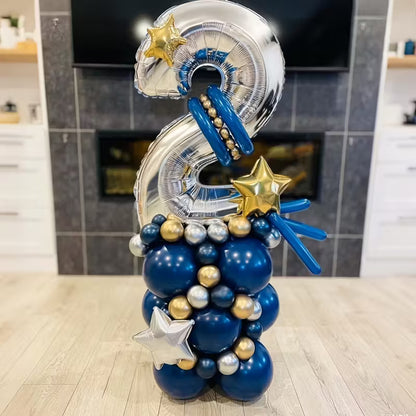Silver number 2 balloon decorated with blue, gold, and silver balloons with star-shaped accents on wooden floor