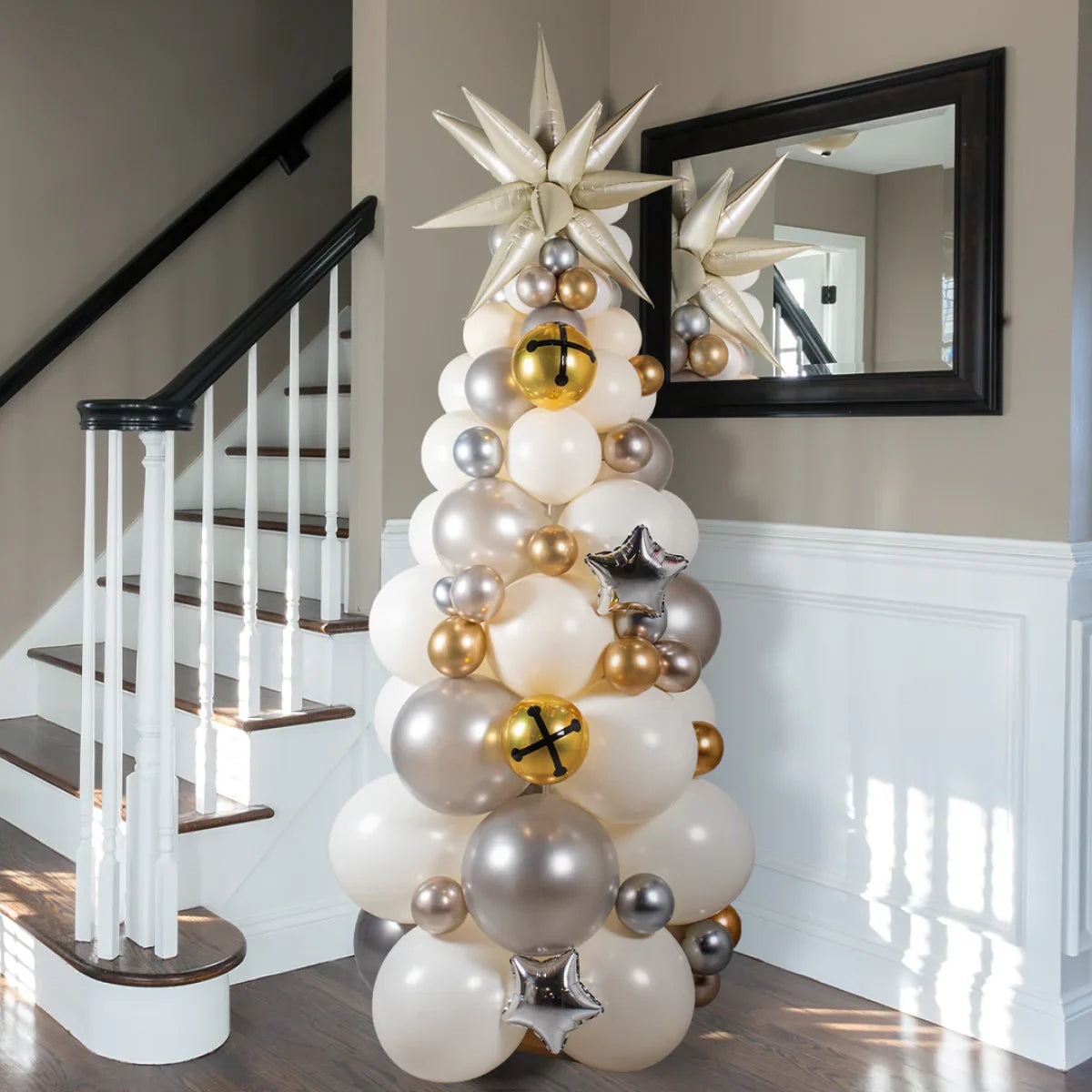 Elegant balloon Christmas tree in white, silver, and gold with star and bell decorations indoors