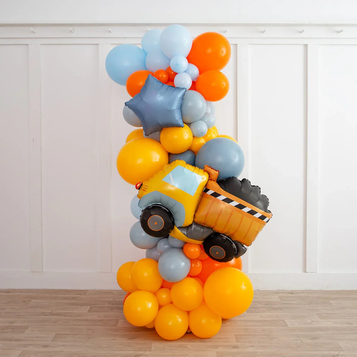 Construction-themed balloon pillar with orange, blue, and gray balloons and a yellow dump truck balloon