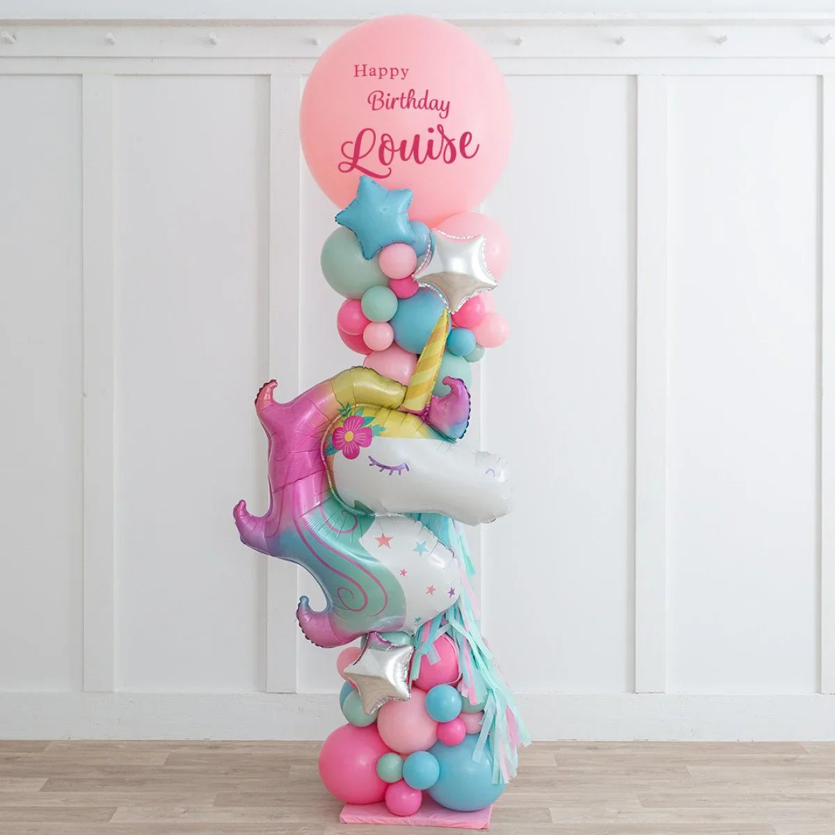 Colorful unicorn balloon sculpture with pastel balloons and "Happy Birthday Louise" pink balloon