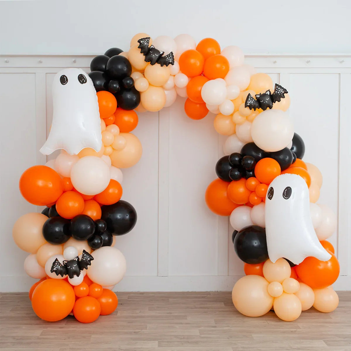 Halloween balloon arch with orange, black, and cream balloons, featuring ghost and bat decorations