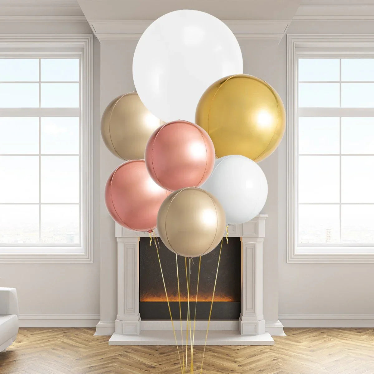 Giant round balloons in copper, gold, white, and beige arranged indoors by a modern fireplace with wood flooring
